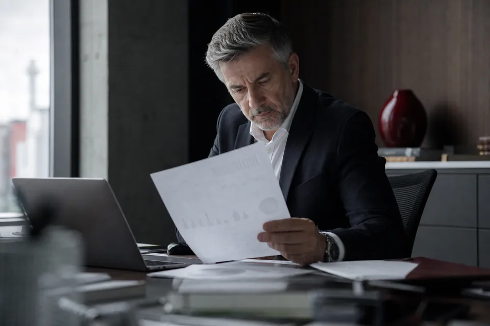 Dyrektor finansowy analizuje wydruk zestawienia przeterminowanych należności